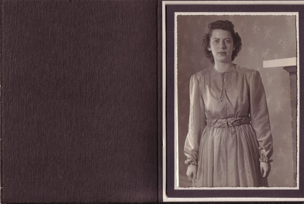 A woman from 1946 faces the camera wearing a long sleeve bridesmaid dress